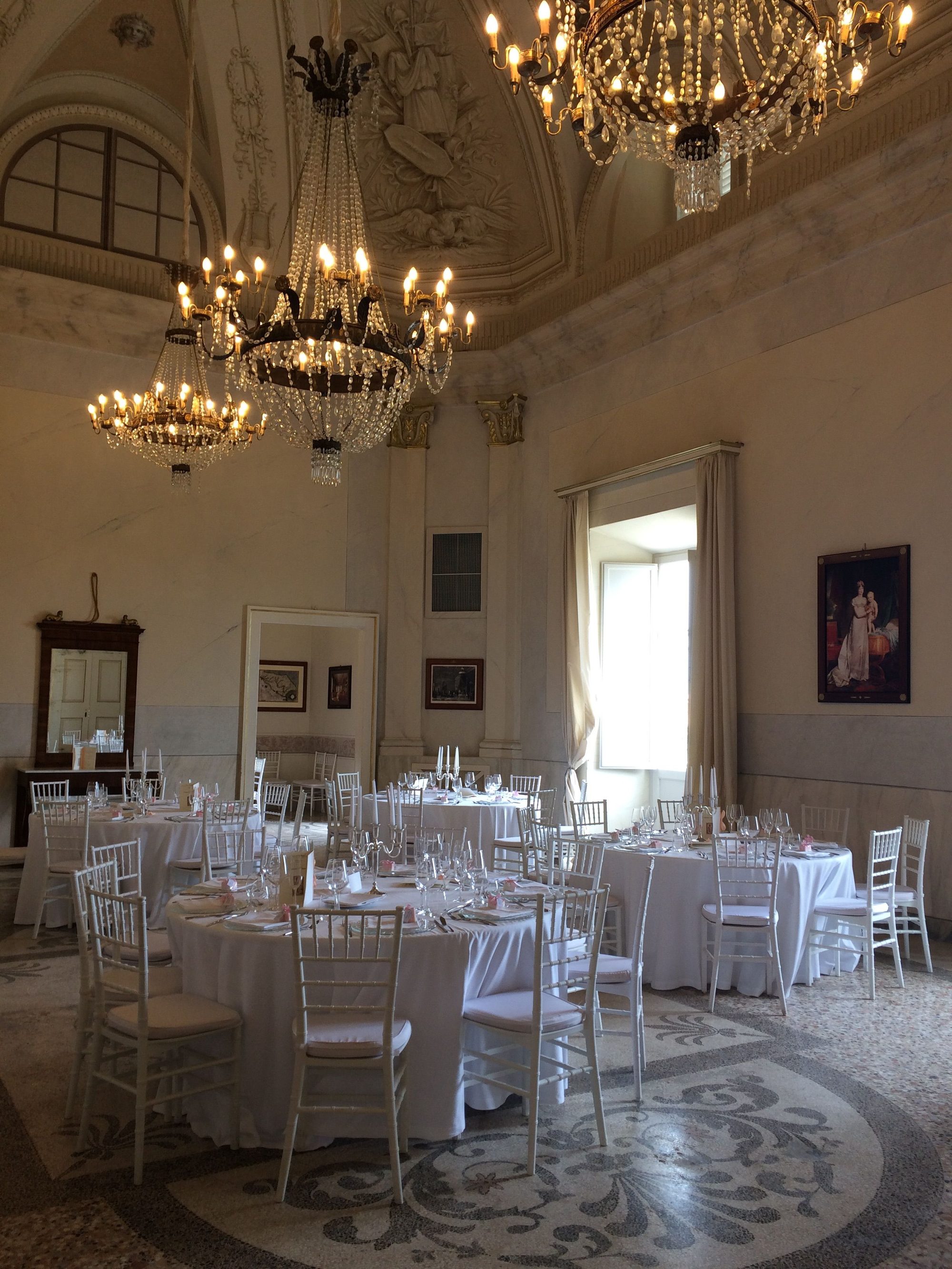 Grand frescoed ballroom with crystal chandeliers set for a wedding reception